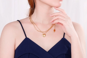 Detail of layered gold stainless steel heart necklace worn on female neck