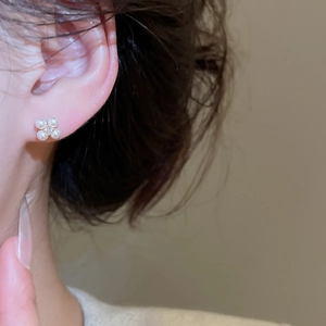 Close-up of model wearing elegant pearl flower earrings with gold plating and zircons