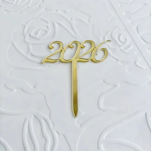 Nahaufnahme der goldenen 2026 Kuchendeko aus Acryl mit Spiegeleffekt für Neujahr