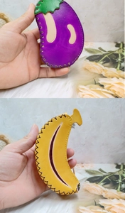 Détail de breloques en cuir faites main en forme d'aubergine et banane avec coutures