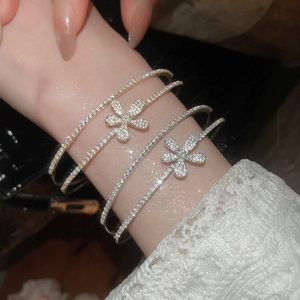Detail of four stackable bracelets with zircon flowers in gold and silver tones