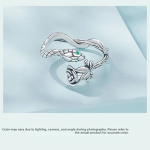Detail of vintage silver snake ring with rose motif and green gemstone eyes decoration
