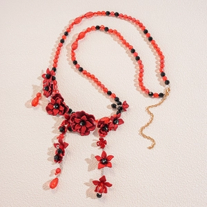 Detail of red acrylic flower necklace with black faceted beads and adjustable chain