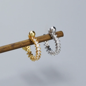 Detailed macro view of gold and silver S925 huggie hoop earrings with sparkling cubic zirconia