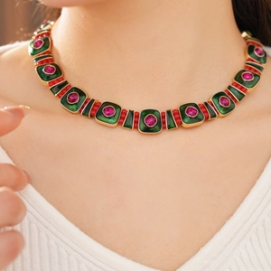 Detail of vintage gold necklace with green enamel and pink gemstones on model