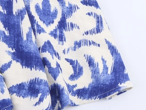 Macro shot of blue and white ikat print fabric with detailed stitching on cotton-linen dress