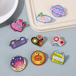 Close-up of colorful enamel pins with heart, star, and motivational quote designs