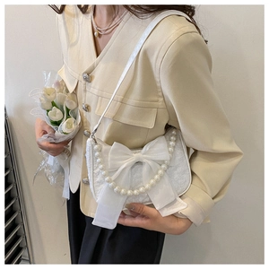 Elegant white bow pearl handbag with jacquard fabric held by a model for a stylish look