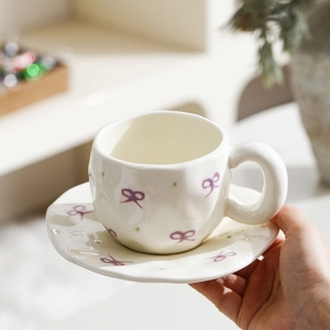 Detailed close-up of cream ceramic cup with purple bow and green polka dots