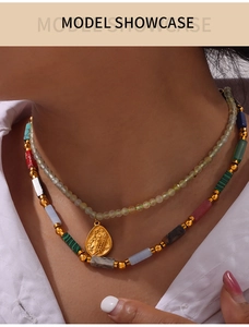 Close-up of layered beaded necklace with natural stones and gold teardrop pendant on model