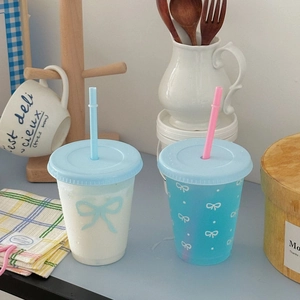 Detail of cute large capacity plastic coffee cups with bows and reusable straws