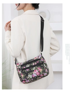 Detail of floral crossbody bag with adjustable strap and multiple zipper pockets