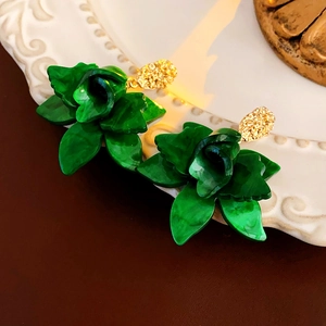 Detailed shot of green rose floral earrings on a white embossed porcelain plate