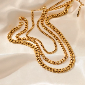 Minimalist gold plated stainless steel Cuban link necklace displayed on beige silk