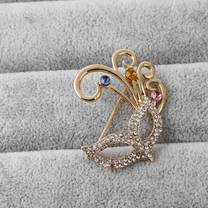Detailed close-up of a masquerade mask brooch with multi-colored crystals on a tray