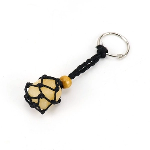 Detail of yellow raw crystal stone in black woven net pouch keychain with wood bead