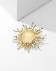 Detail of sunburst brooch featuring opal stone and shimmering pavé zircons in gold
