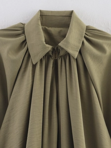 Gros plan d'un blouson bomber olive avec plis aux épaules et détail de fermeture éclair