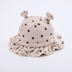 Detail of baby sun hat with brown polka dots, cute ears, and white lace bow edging