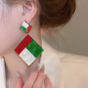 Detail view of large geometric resin drop earrings with red, green, and white color blocks