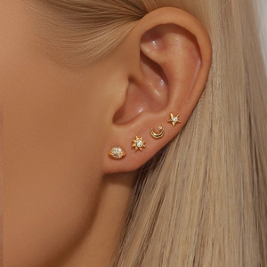 Close-up of model wearing gold S925 silver earring set with star, moon, and sun motifs