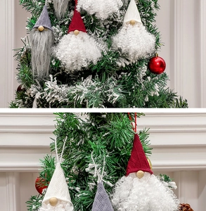 Close-up of knit Christmas gnome ornaments hanging on a snowy tree for festive decor