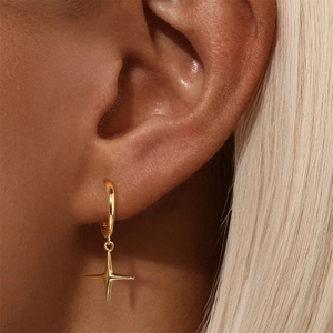 Close-up of a gold star charm earring worn by a model showcasing elegant metal texture