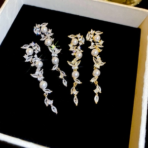 Detail shot of long gold tassel earrings with artificial pearls and zircons on black velvet