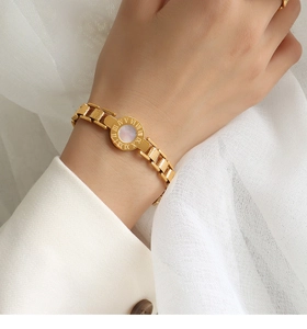 Detail of gold Roman numeral bracelet featuring a white mother-of-pearl center and hammered links