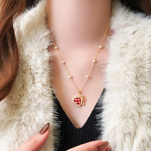 Gold plated necklace with red heart pendant and pearls worn on a model's neck