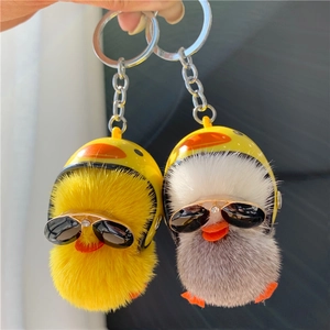 Detail of plush duck keychains with yellow helmets and black sunglasses in gray and yellow