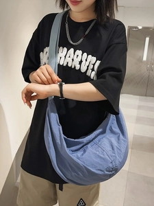 Sac hobo bleu en nylon type dumpling avec bandoulière large porté par un mannequin homme