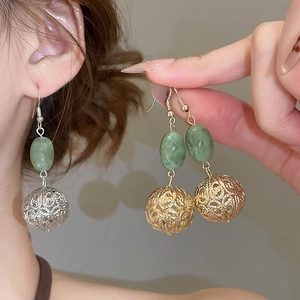 Vue détaillée des boucles d'oreilles pendantes en résine avec perles vertes et métal évidé