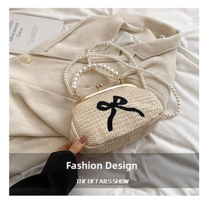 Détail d'un sac en paille avec nœud noir, fermoir doré et bandoulière en perles