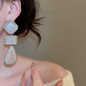 Close-up of geometric resin drop earrings with gold foil details on a model