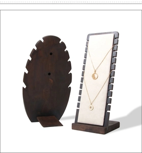 Detail of leaf-shaped solid wood jewelry stand with walnut finish and beige velvet panel