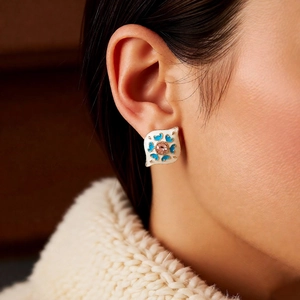 Close-up of vintage enamel earring with blue heart and pink gemstone on a model