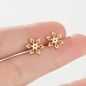 Macro view of gold snowflake stud earrings held in fingers for size comparison