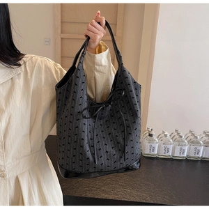 Detail of grey bucket bag showing jacquard bow texture and stylish ribbon decorative knot