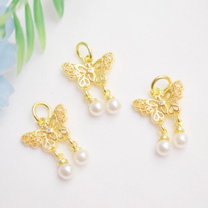 Detailed macro view of 14K gold-plated bow pendants with small rhinestones and pearls