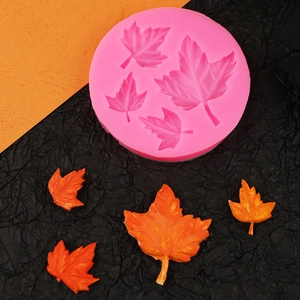 Pink silicone mold featuring five maple leaf cavities with orange finished cake decorations