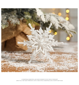 Detailed view of white flocked snowflake ornament with silver string on Christmas tree