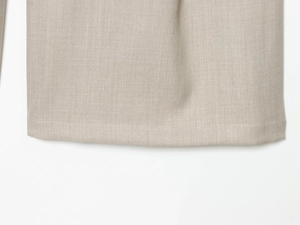 Close-up of beige wool pleated trousers showing fine stitching and woven fabric texture