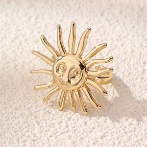 Detail of vintage gold sun face ring with radial rays on a stone surface