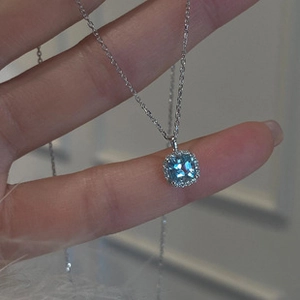 Macro view of blue sapphire necklace pendant with diamond halo on silver chain