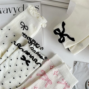 Detailed flat lay of cream mid-calf socks with bow embroidery and ruffled edge design