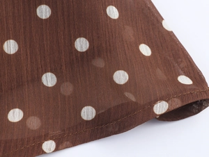 Vue macro détaillée du tissu en mousseline marron à pois blancs et couture précise