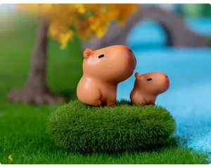 Macro shot of two cute capybara resin figurines set on a miniature grass landscape