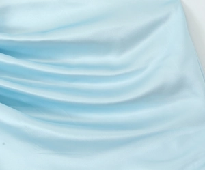Close-up of light blue silk fabric with elegant drape and smooth soft texture