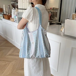 Detail of light blue floral canvas tote bag with Scakka label shown in cafe setting
